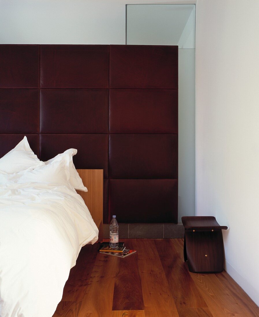 Bed against cushioned wall covered in brown leather in designer bedroom