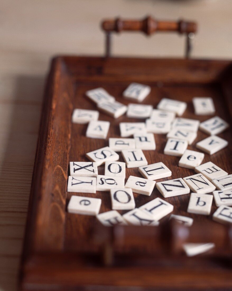 Spielsteine mit Buchstaben auf Holztablett