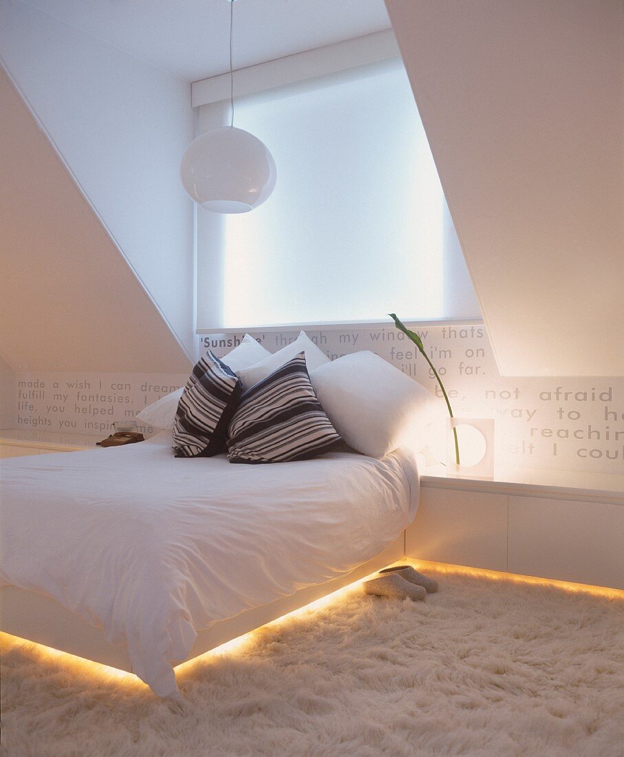 Doppelbett und Sideboard mit eingebautem indirektem Licht im modernen Dachzimmer