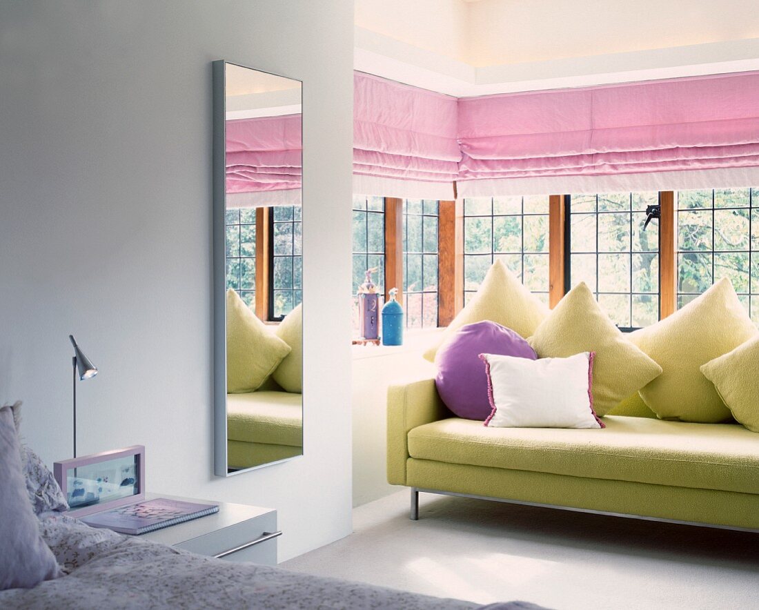 Modernes Sofa mit drapierten Kissen im verglasten Erker eines Schlafraumes