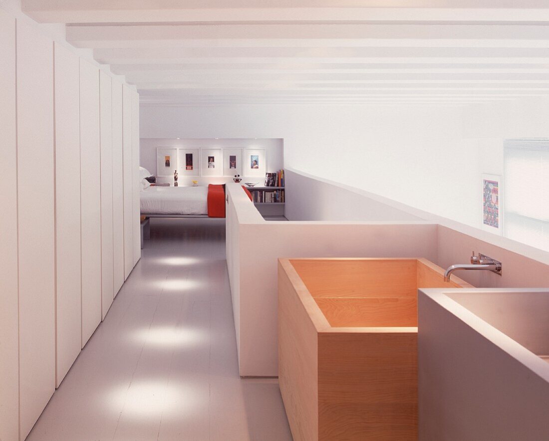 Galerie mit freistehender Badewanne aus Holz vor offenem Schlafraum