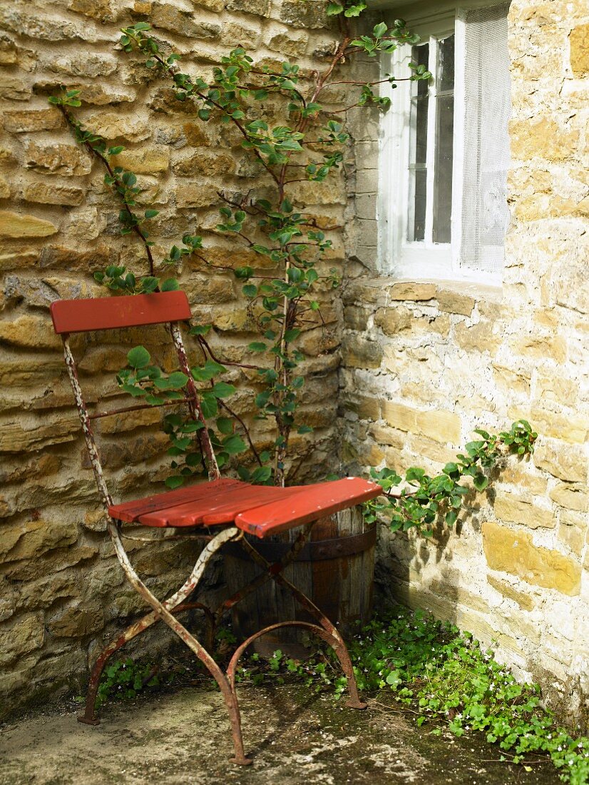 Alter verrosteter Stuhl in Hausecke im Garten