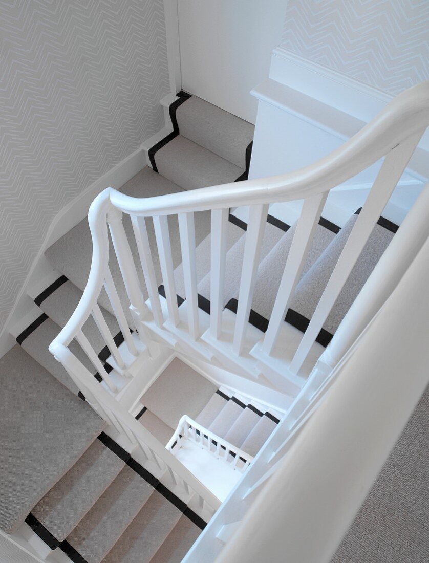 Traditional wooden stairs in stairwell with grey and black stair runner