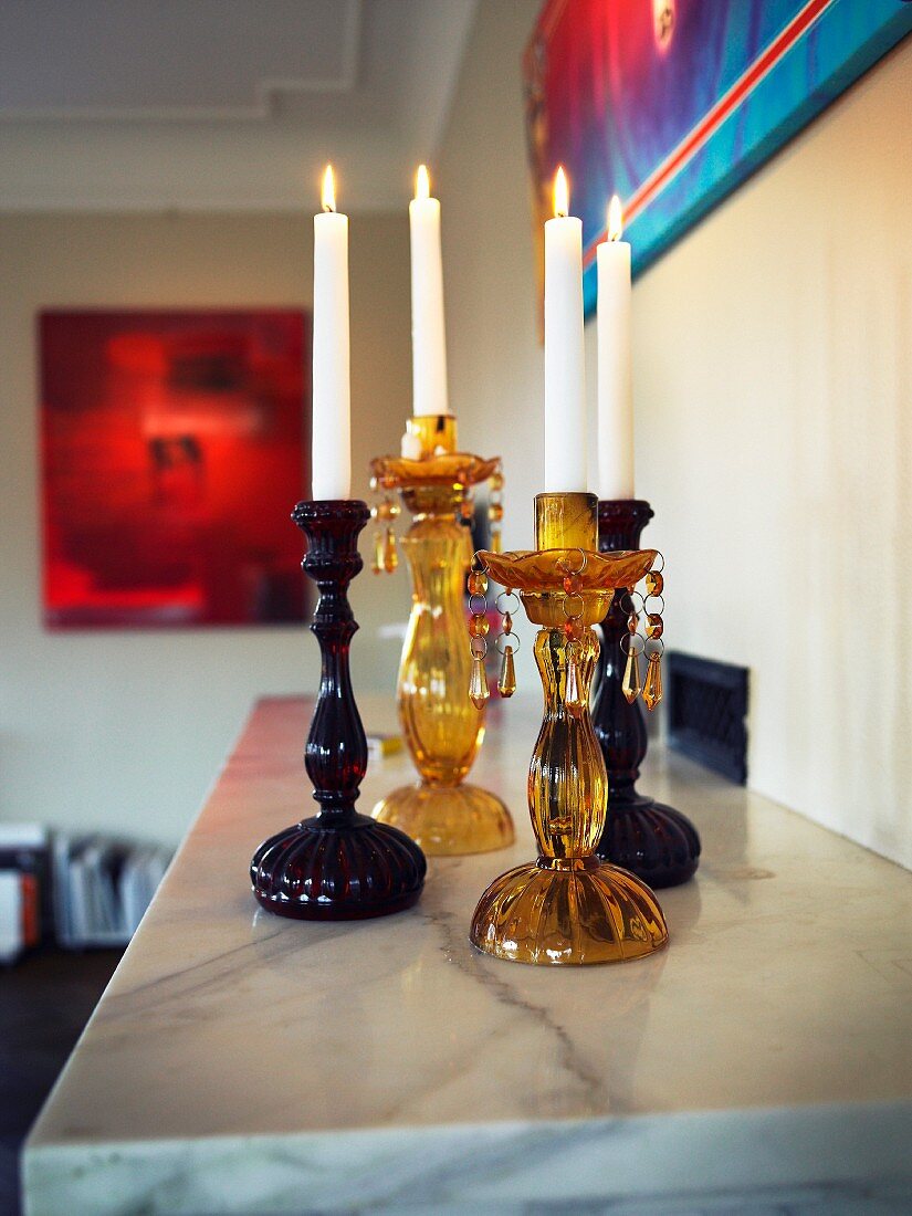 Traditionally-shaped, glass candlesticks on marble mantelpiece