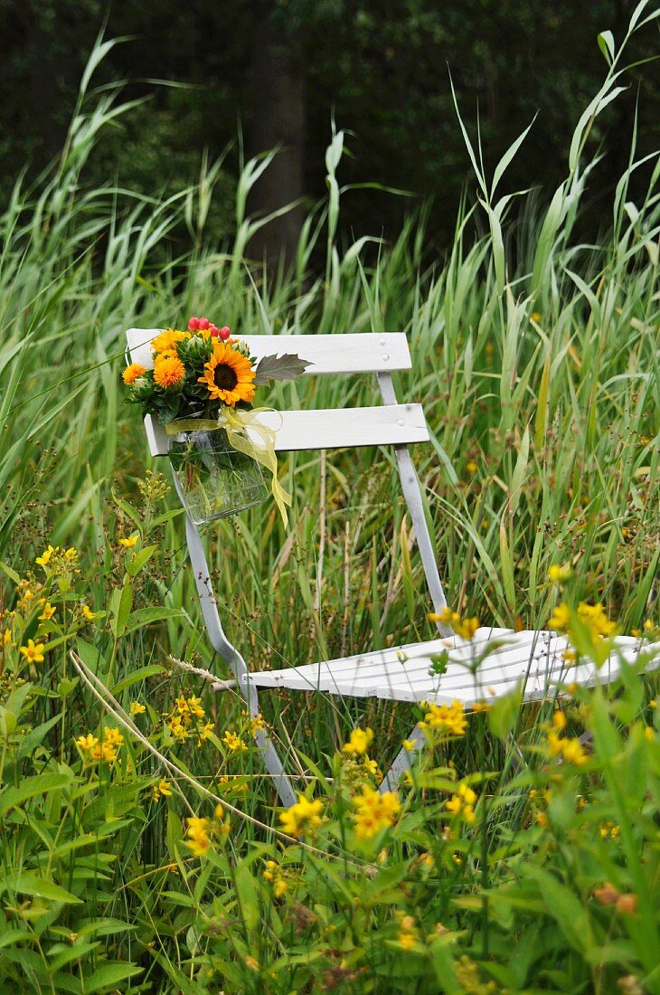 Folding chair decorated with flowers in summer meadow