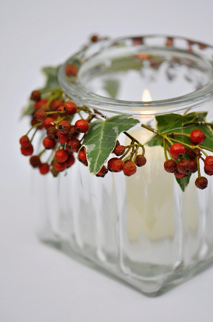 Windlicht aus Glas mit Beeren & Blättern dekoriert