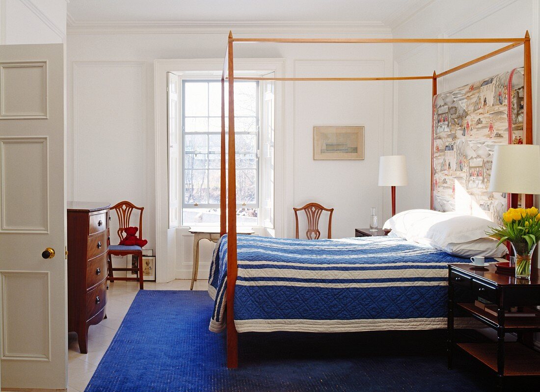 Schlafzimmer mit Himmelbett, blauer Tagesdecke & blauem Teppich
