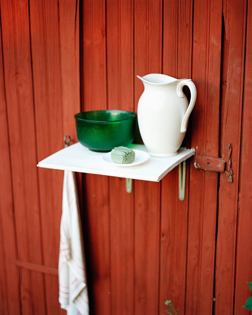 Still-life of washing utensils on shelf mounted on rust-red wall of house