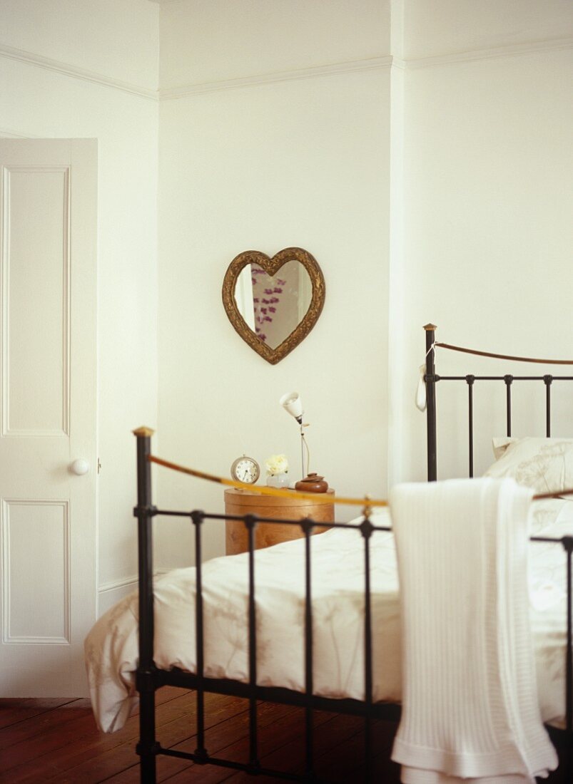 Traditionelles Schlafzimmer mit Metallbett im Antik-Stil und herzförmigem Spiegel