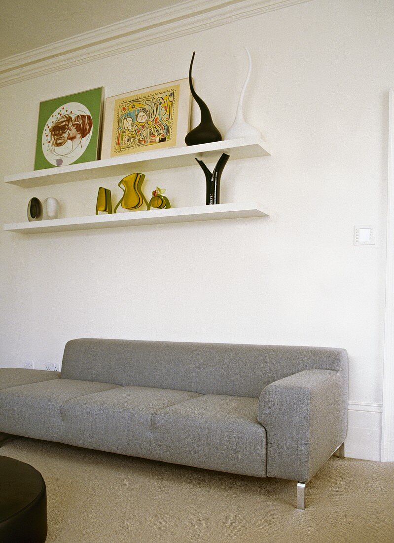 Shelves with objet d'art and pictures above plain, grey recamier