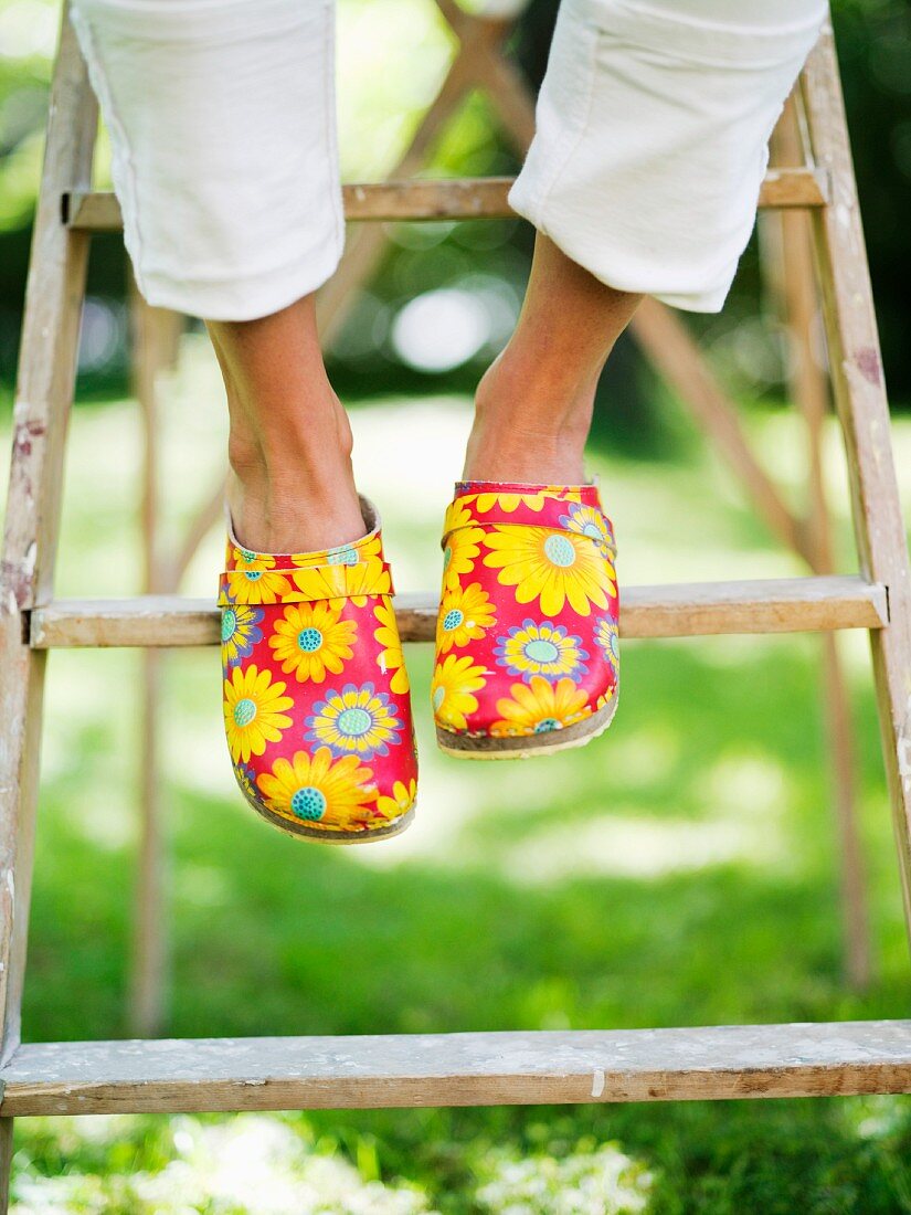 Feet in clogs with cheerful floral pattern