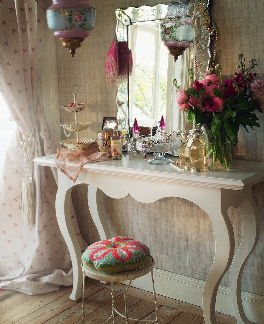 Dressing table with cosmetics and jewelry boxes in front of a mirror