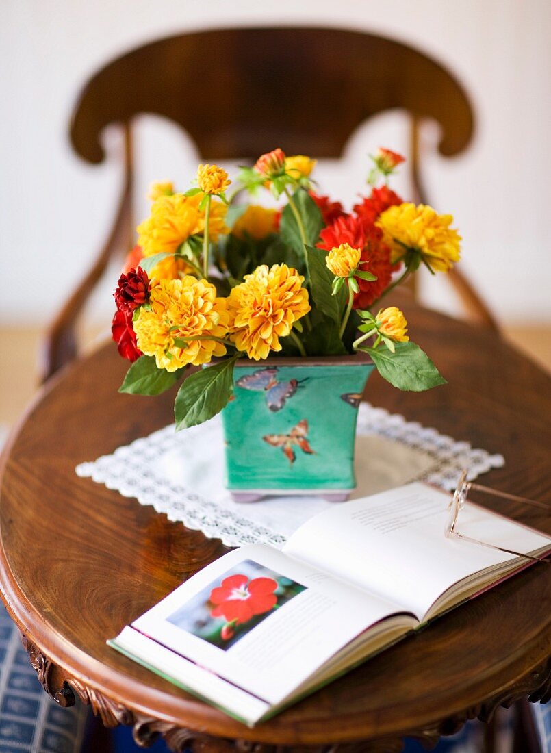 Yellow and red flowers in a ceramic pot on an antique wooden side table
