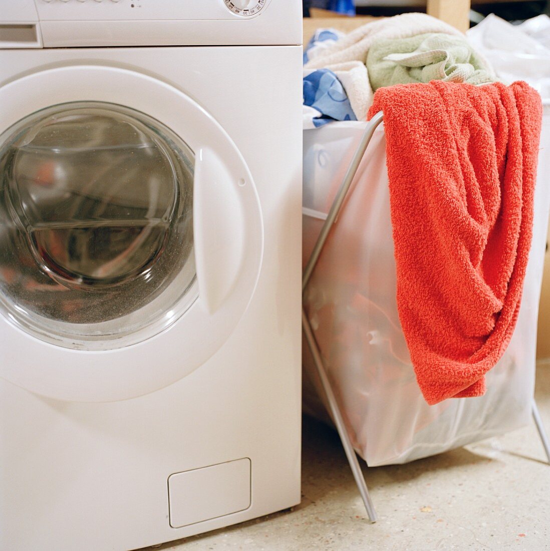 Laundry basket filled with washing next to a washing machine