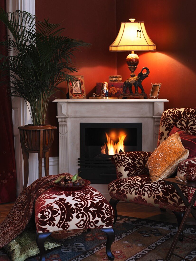 Antique chair with matching stool in front of a fireplace and blazing fire