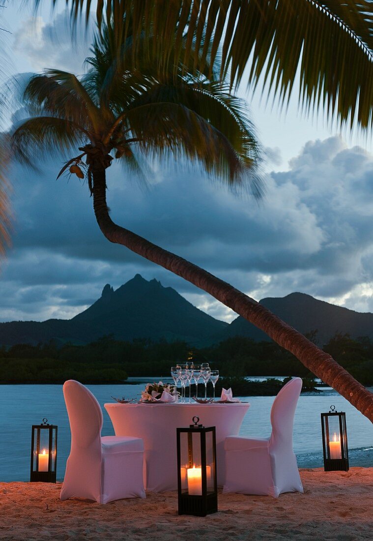 Festlich gedeckter Tisch mit weisser Husse am abendlichen Strand (Mauritius)