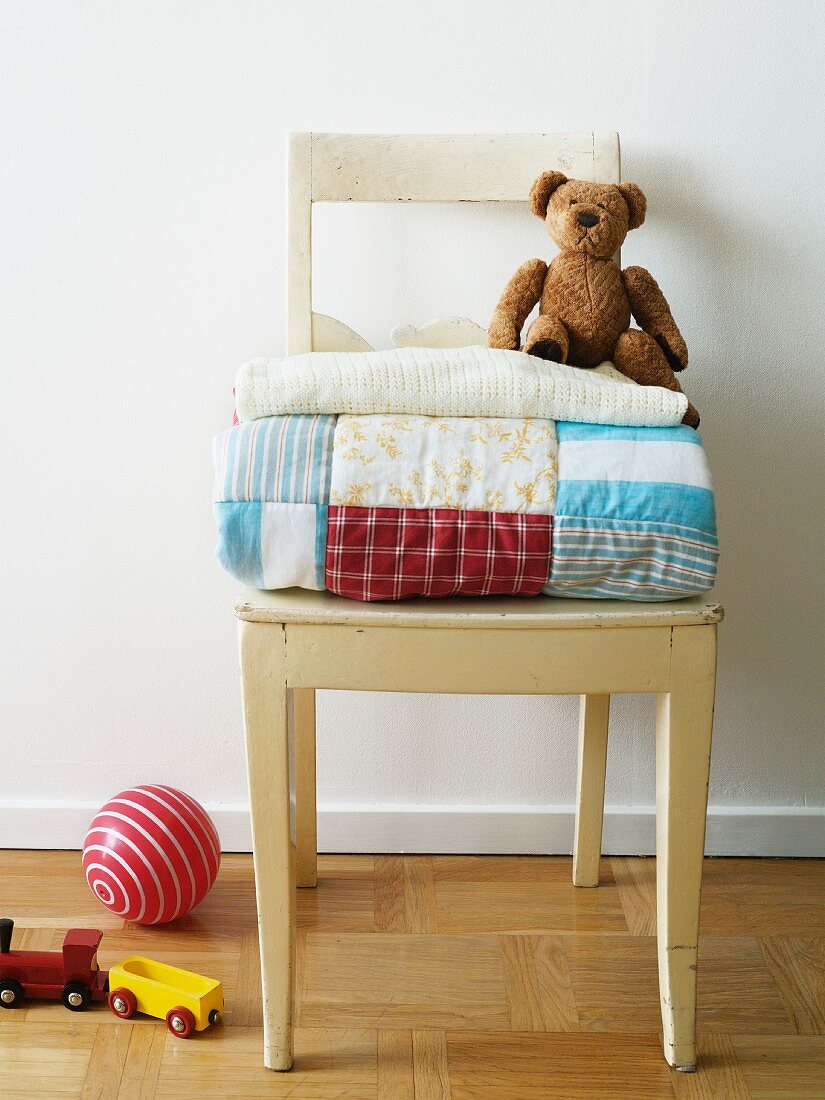 Patchwork quilt and teddy bear on a wooden chair