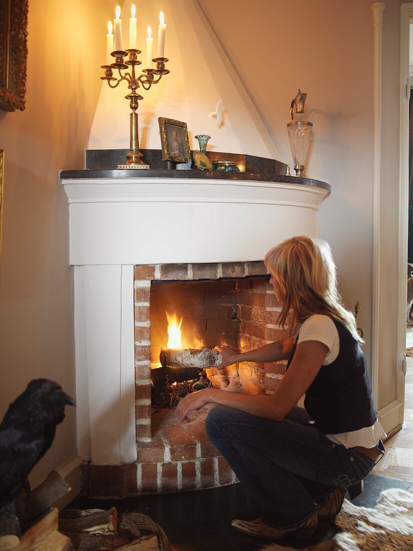 Lady putting wood in a fireplace