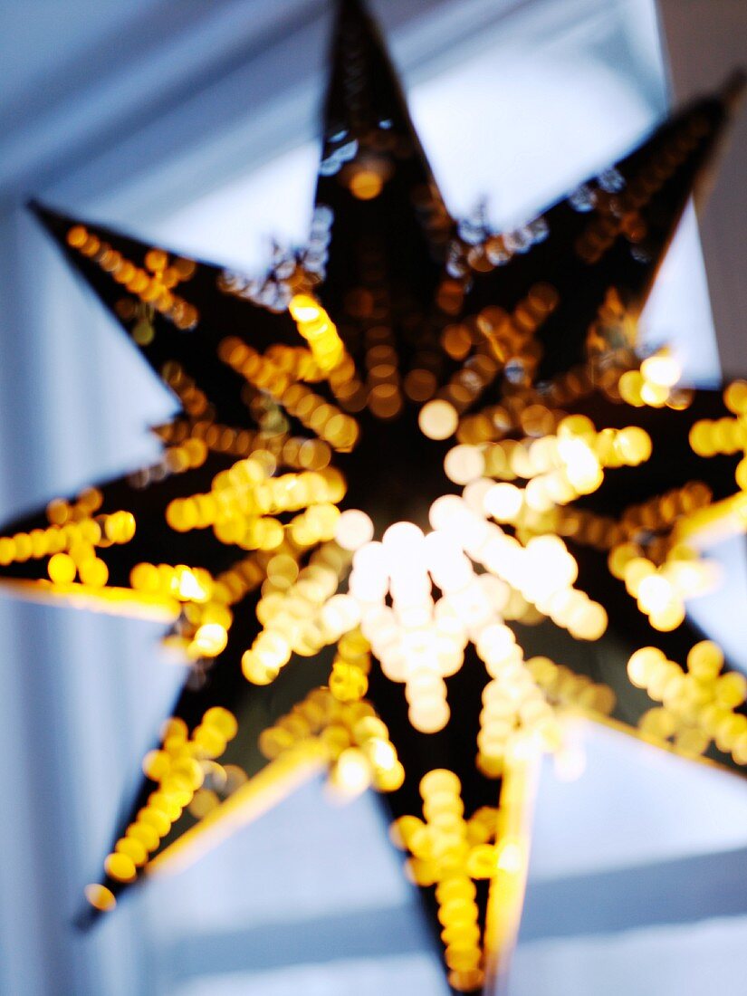 Sternförmige Laterne vor dem Fenster als Weihnachtsdeko