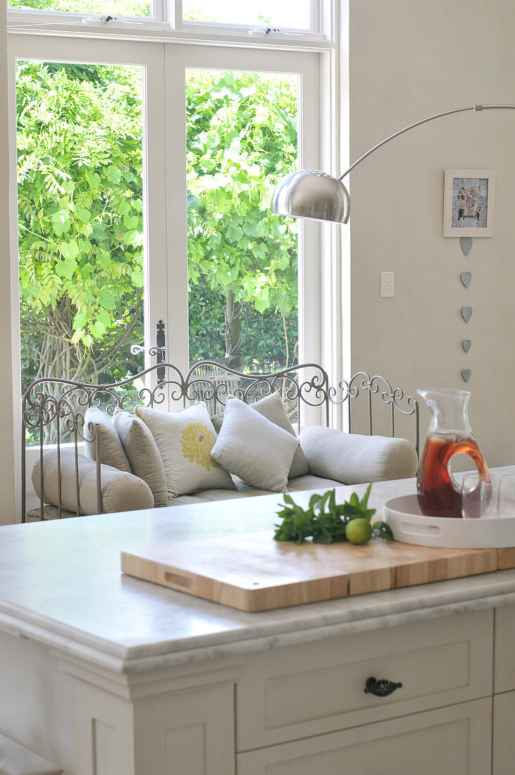 Kitchen island with marble top and metal-framed bench in front of terrace door