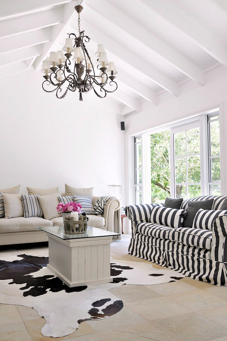 Couch mit schwarz weiss gestreiftem Bezug und Tierfell auf Boden im schlichten, renovierten Landhaus