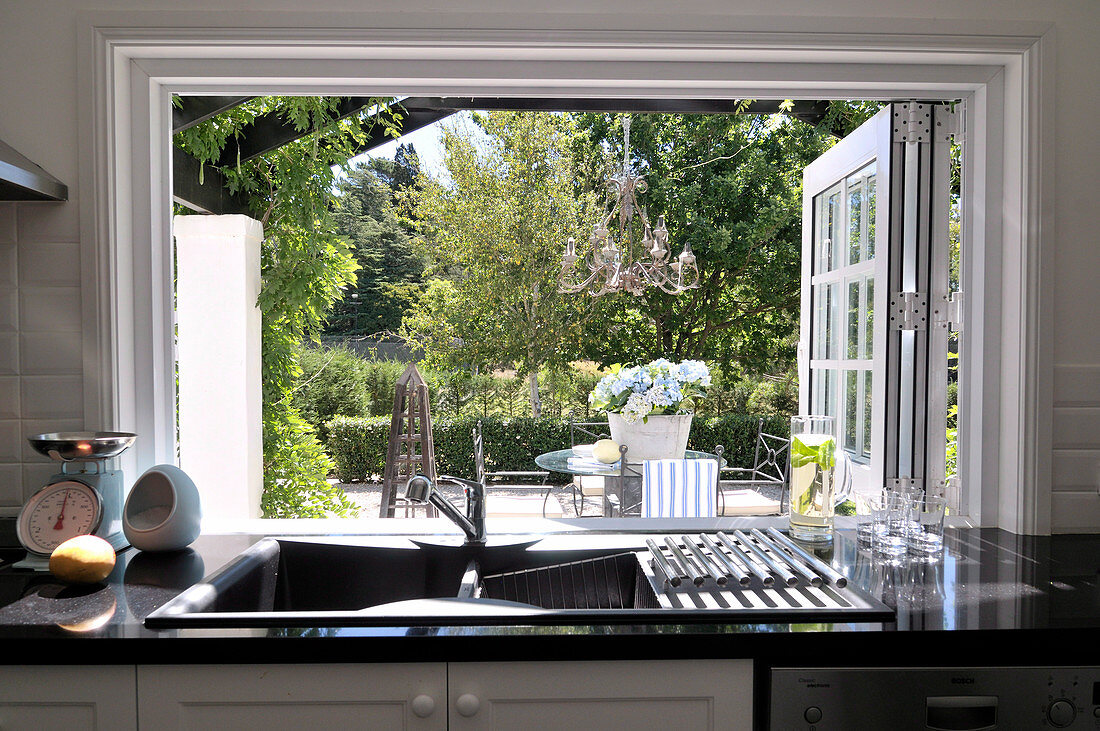 Kitchen counter beneath open window with view of garden