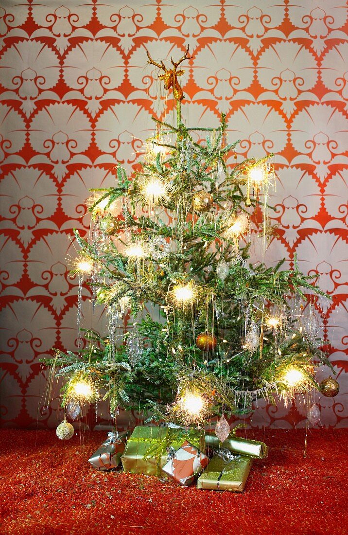 Christmas tree with burning stars in front of a wall with wallpaper