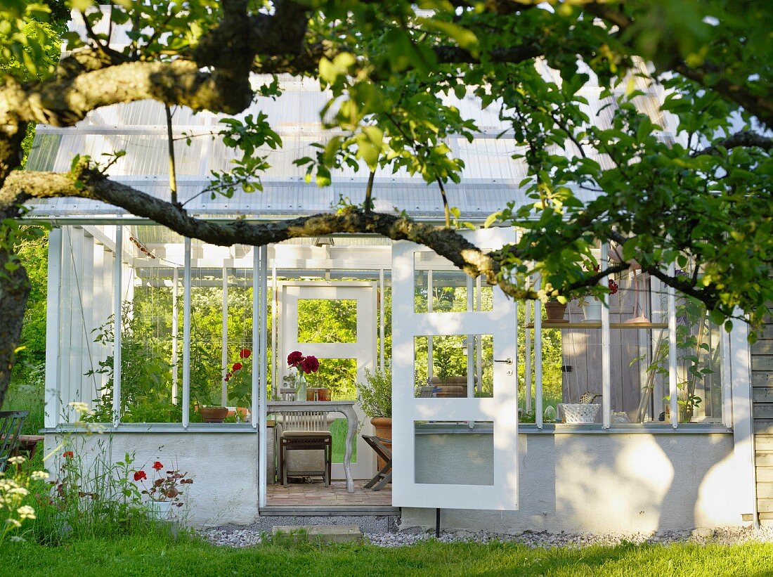Blick in traditionellen Gartenpavillon aus Glas mit offenstehender Tür