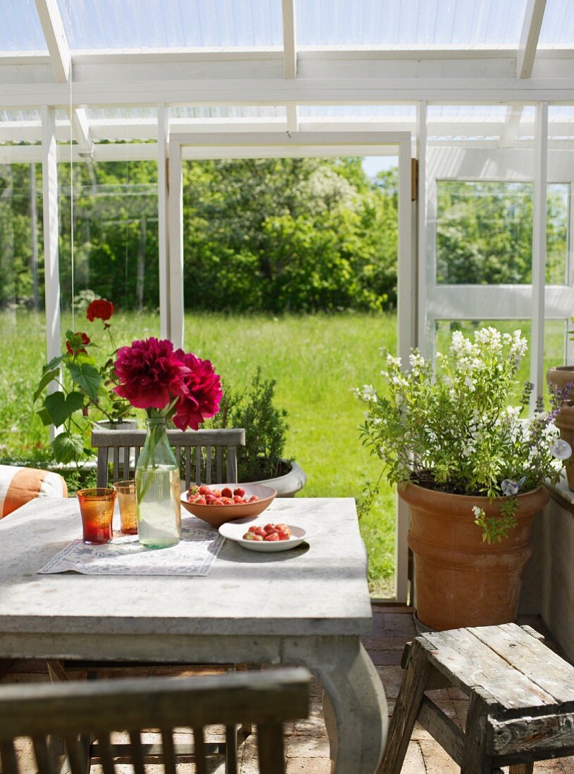 Rustic wooden table in a conservatory with a view of the garden