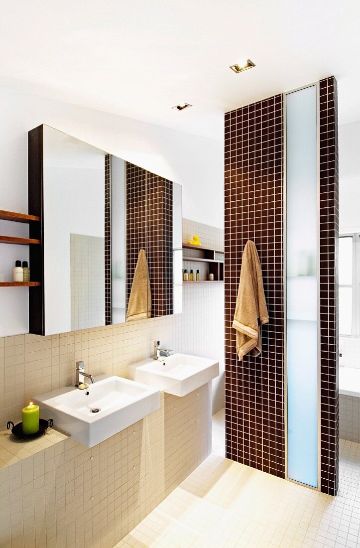 Brown and beige bathroom with two sinks and partition screening bathtub