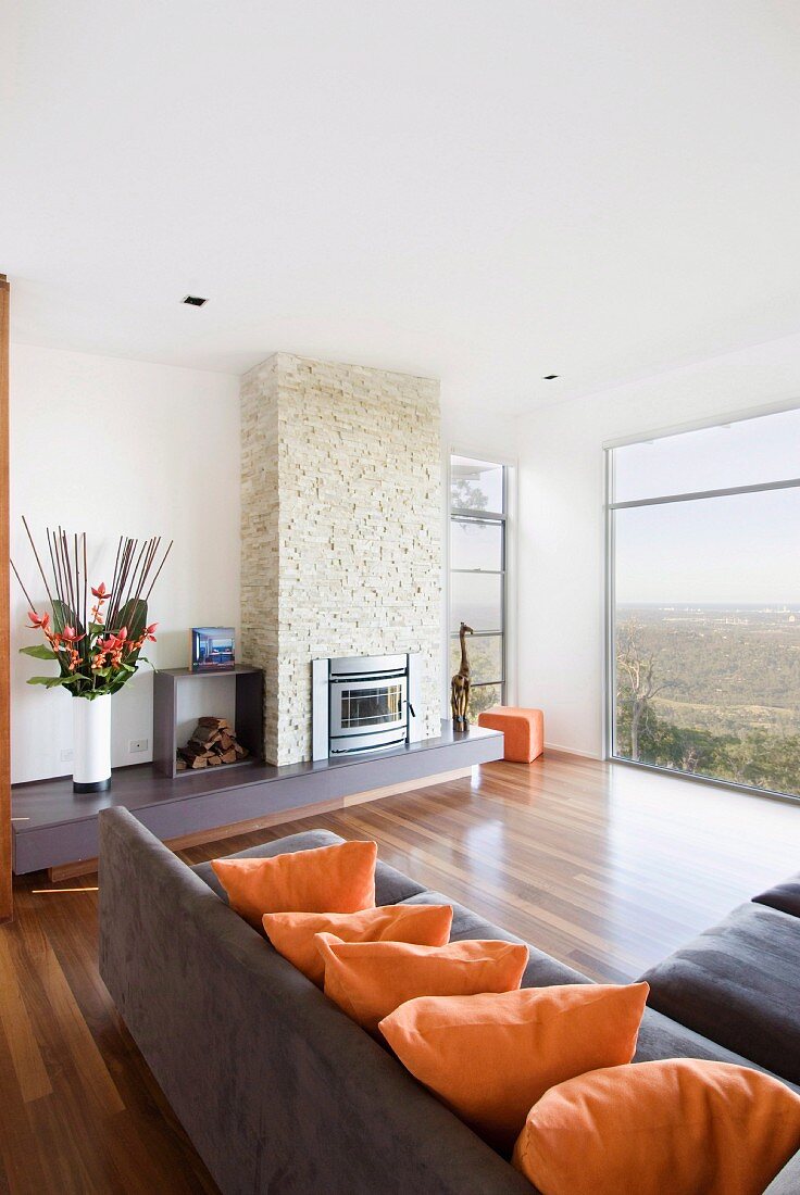 Elegant living room with corner sofa, fireplace and panoramic view of landscape