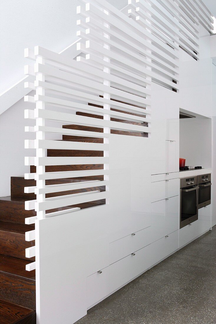 Installation below stairs and balustrade of white, horizontal wooden slats