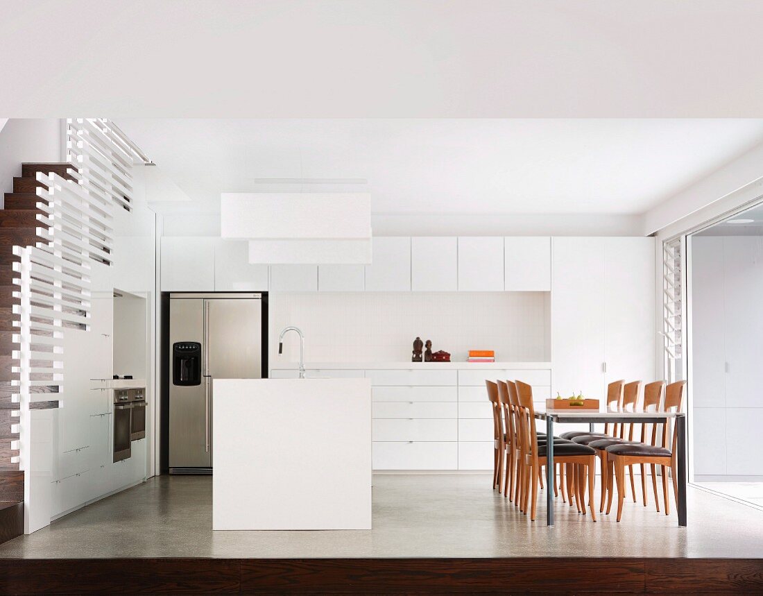 White, designer kitchen with dining area and staircase
