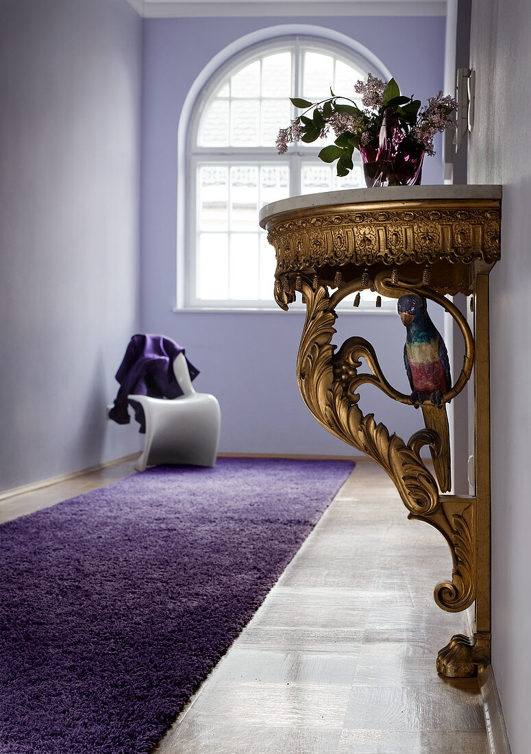 Rococo console table in lilac period hallway; white Panton chair below arched window in background
