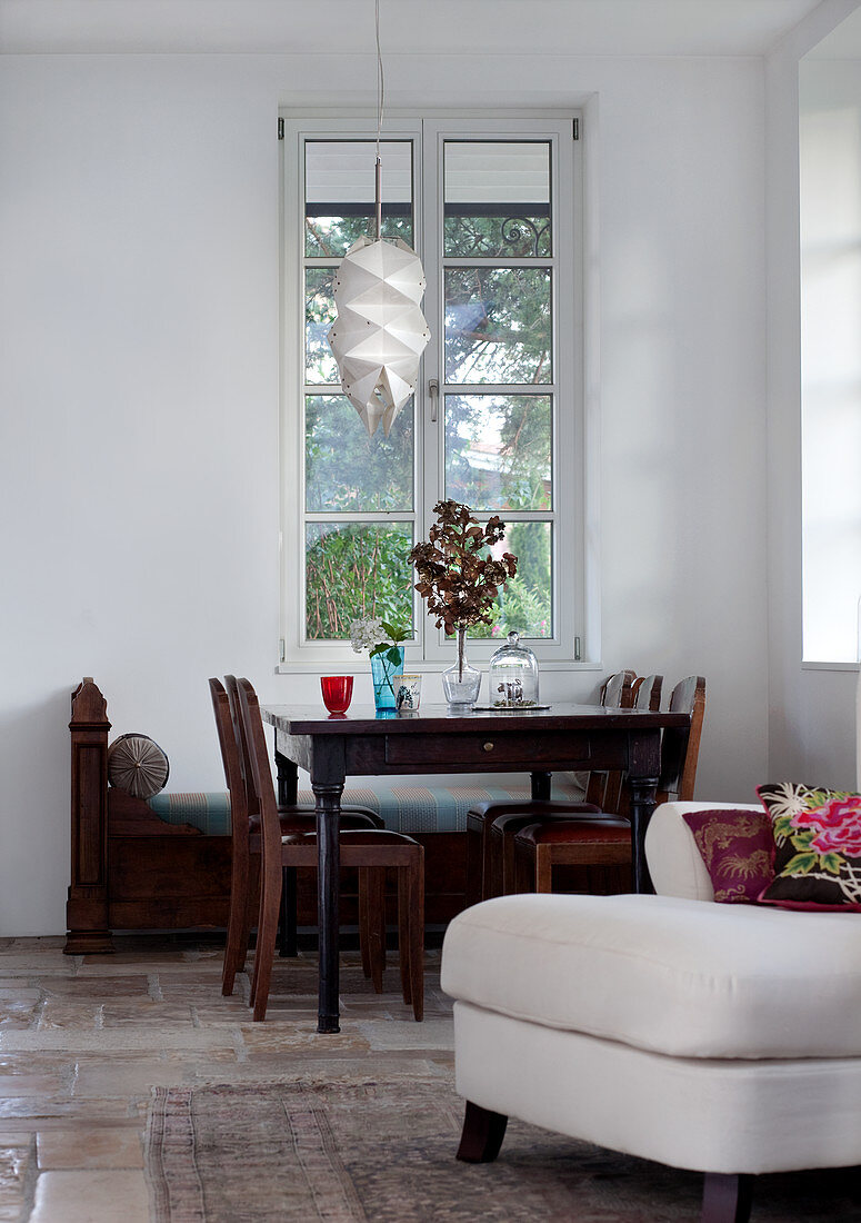 Antiker Esstisch und Stühle vor hohem Sprossenfenster im Wohnzimmer mit Natursteinboden