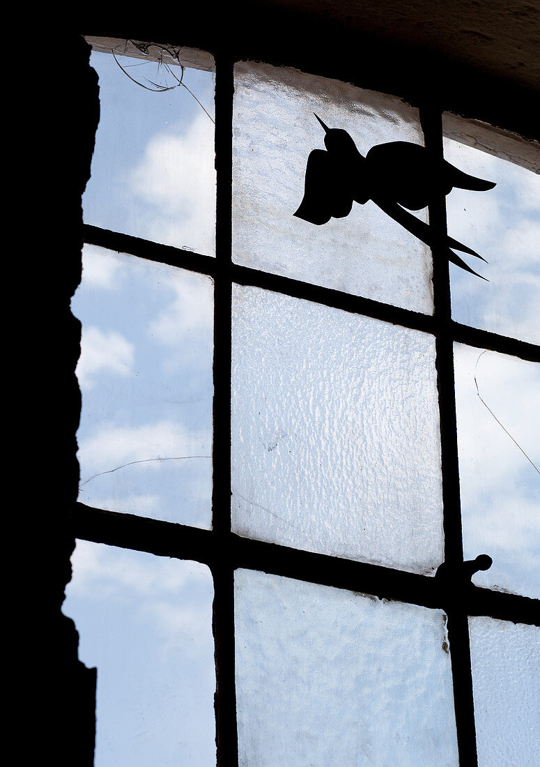 Deko-Vogel an Scheibe eines Sprossenfensters befestigt