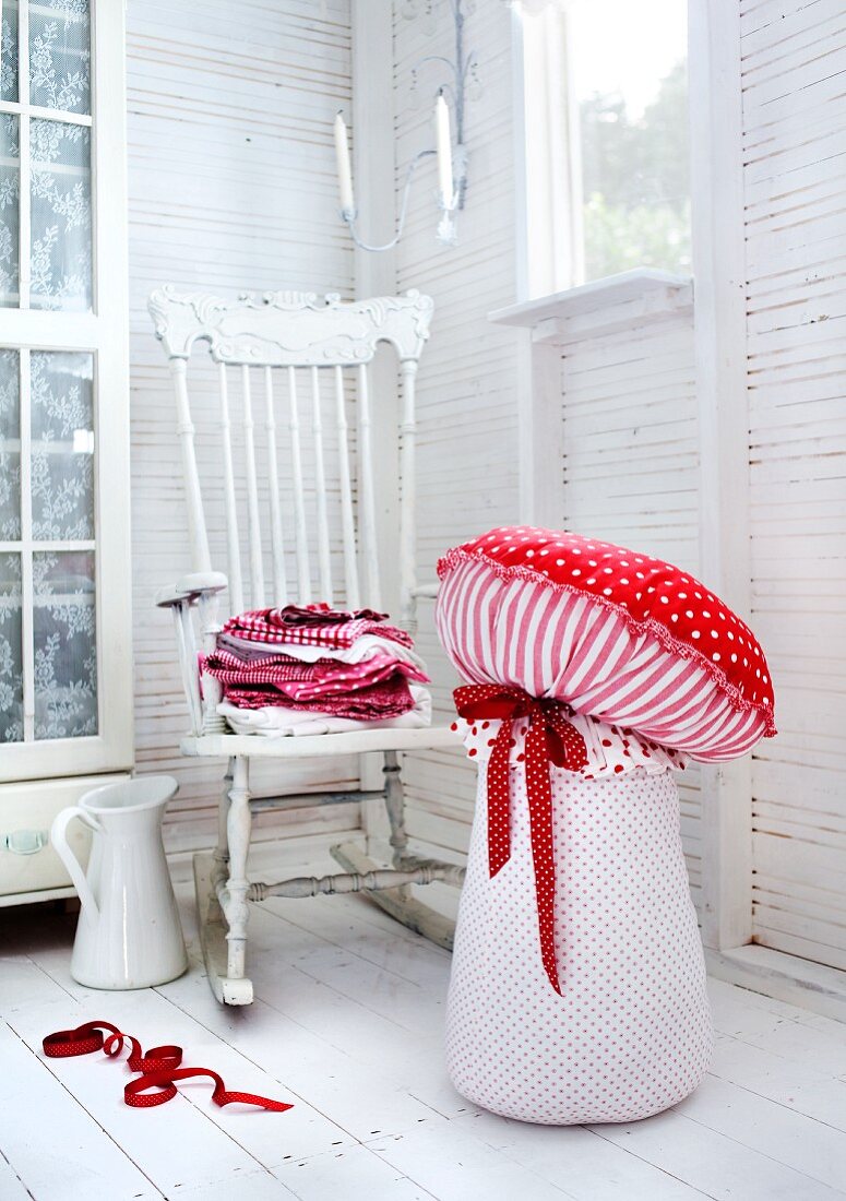Decorative toadstools in a the corner of a white room with a vintage swivel chair and porcelain pitcher