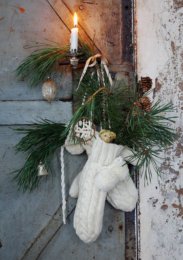 Handschuhe mit Ästen, Baumanhängern und Zapfen als Adventsschmuck für die Tür