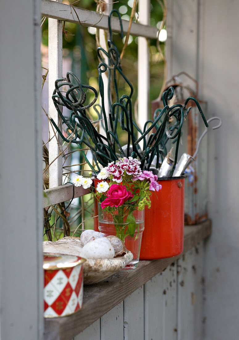 Rankhilfen, Blumen und Deko im Fenster des Gartenhauses