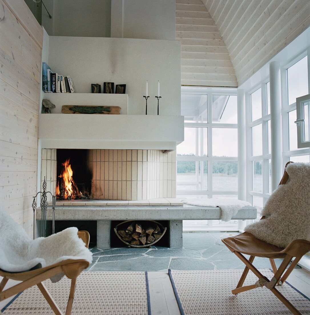 Armchair with white animal hide in front of an open fireplace