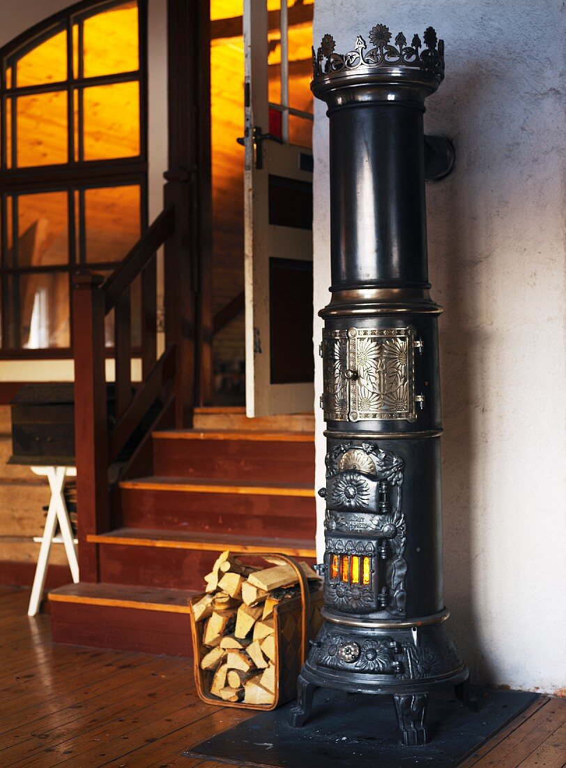Old cylindrical cast iron stove next to stairs in a living room with an open door