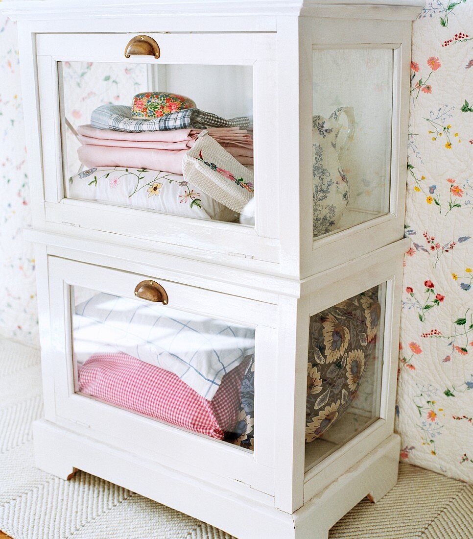 Table linens and pillows stacked in a glass-front cabinet
