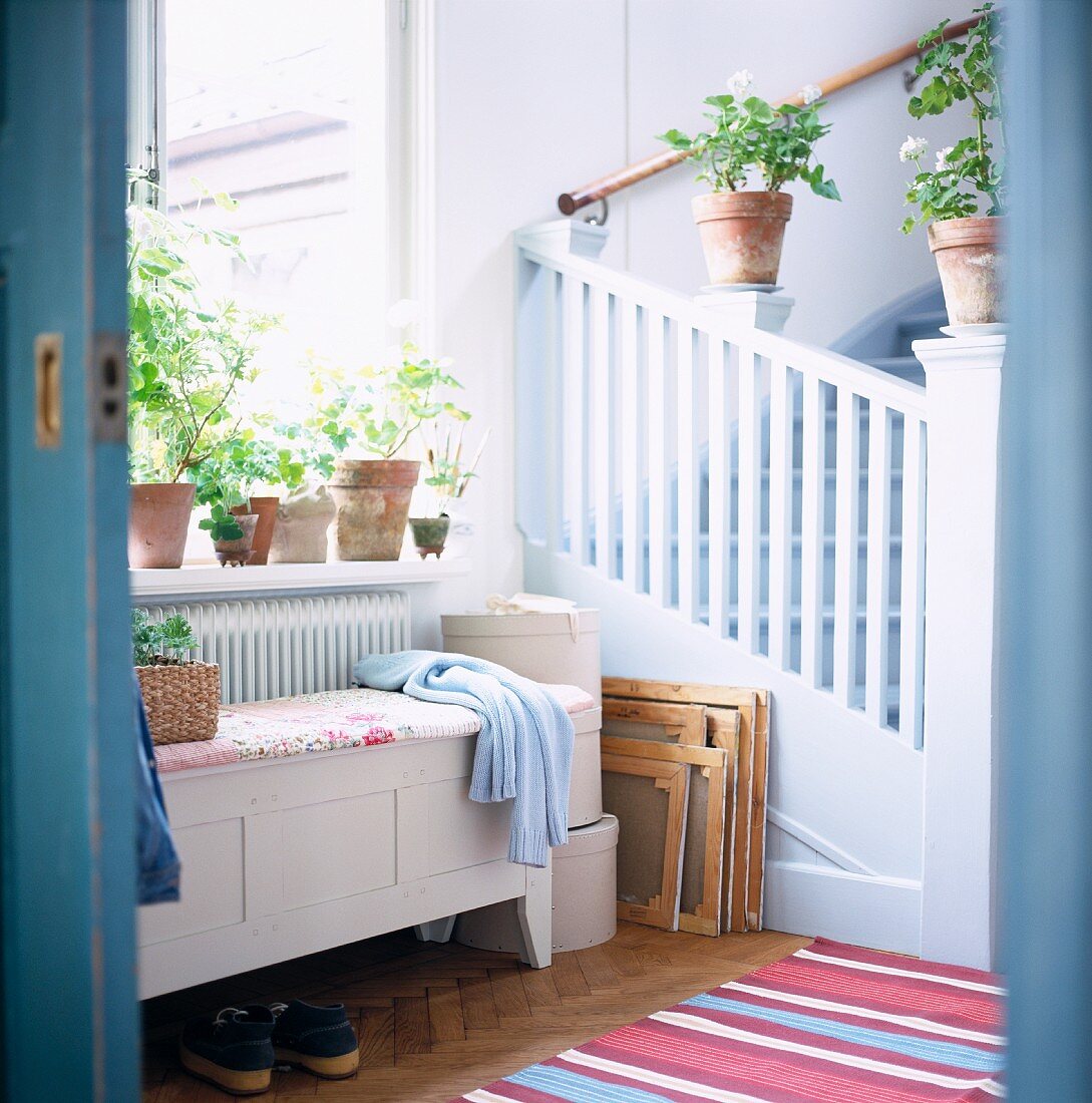White wooden bench in front of a window in a country stairwell