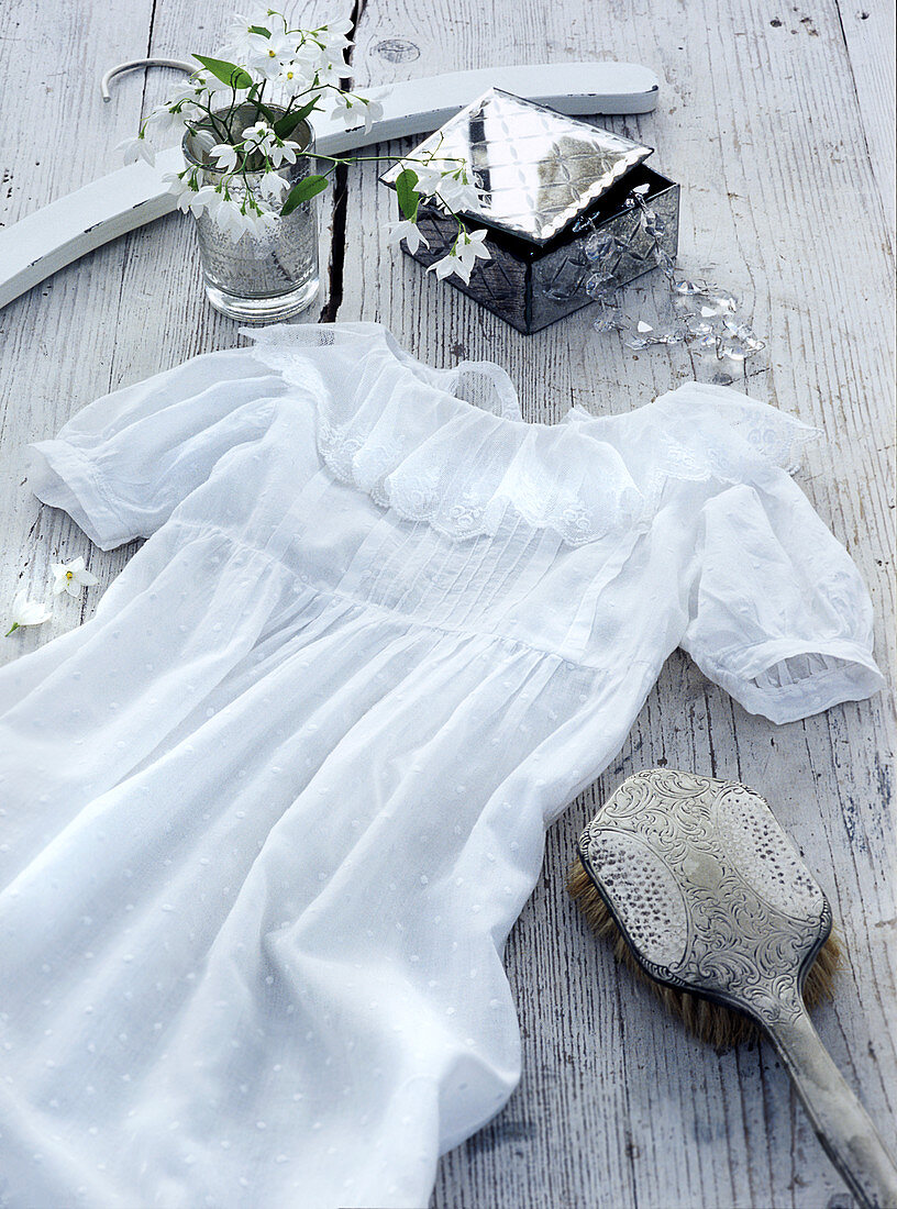Weisses Kleidchen und Schmuckkästchen auf Holzuntergrund