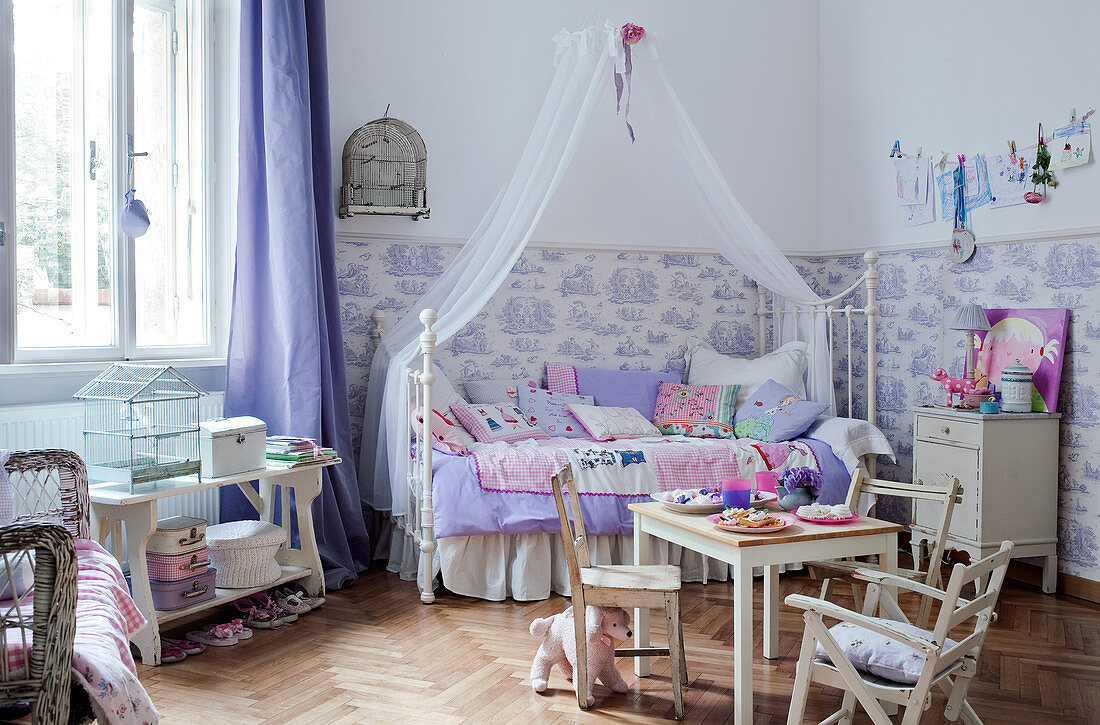 Ländliche Kinderstühle und Tisch vor Himmelbett in grossem Kinderzimmer mit halbhoch tapezierter Wand