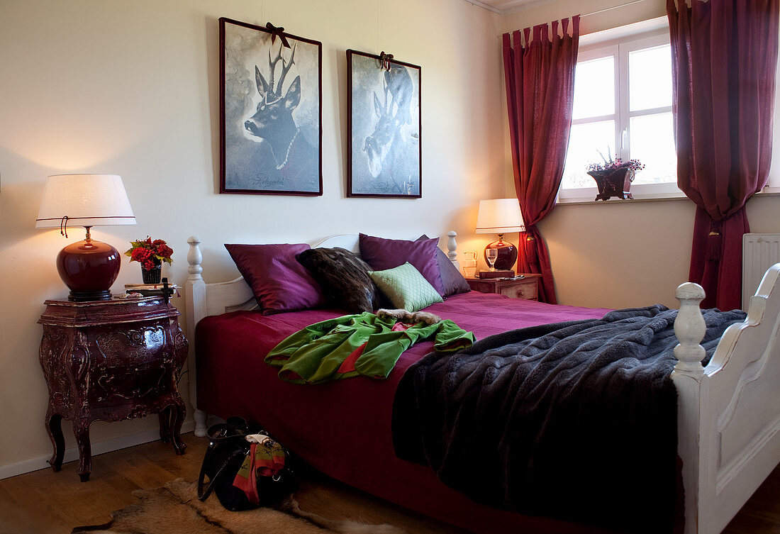 Schlafzimmer mit weinroten Stoffen und Nachttisch im Barockstil