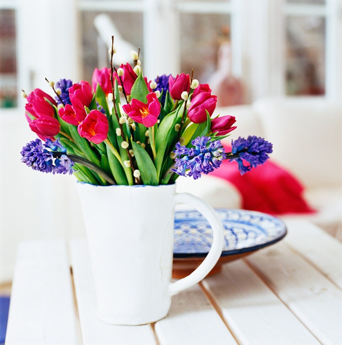Frühlingsstrauss mit roten Tulpen im weissen Krug