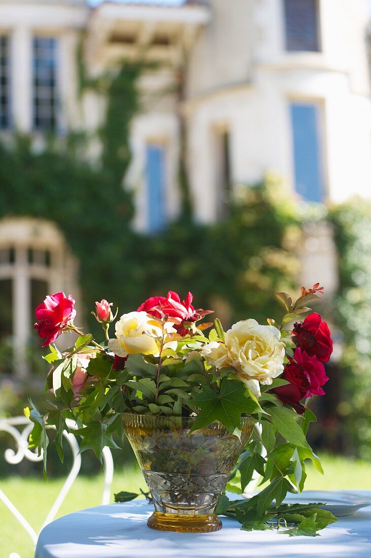 Bouquet of roses on garden table in front of villa