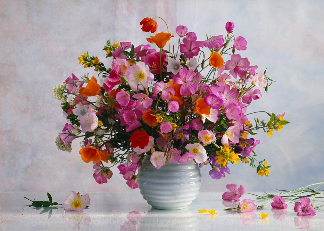 Colourful spring bouquet in spherical vase against light, clouded wall