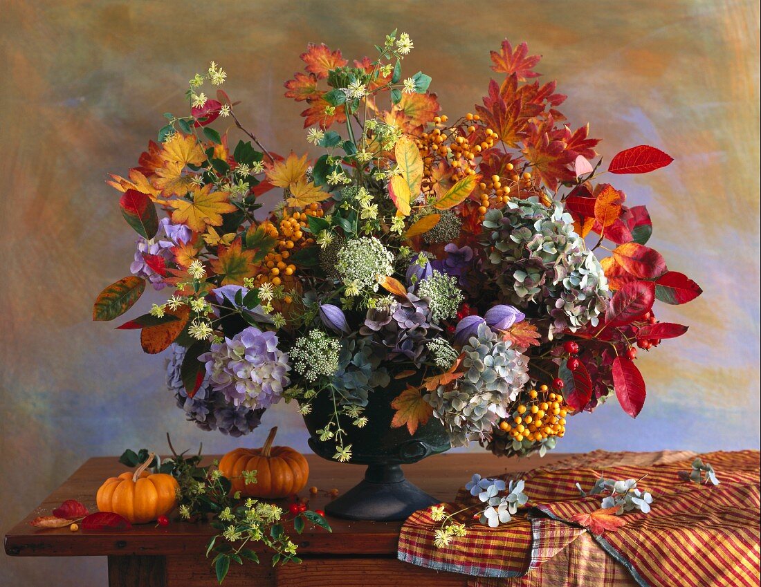 Autumnal bouquet and ornamental squashes on wooden table